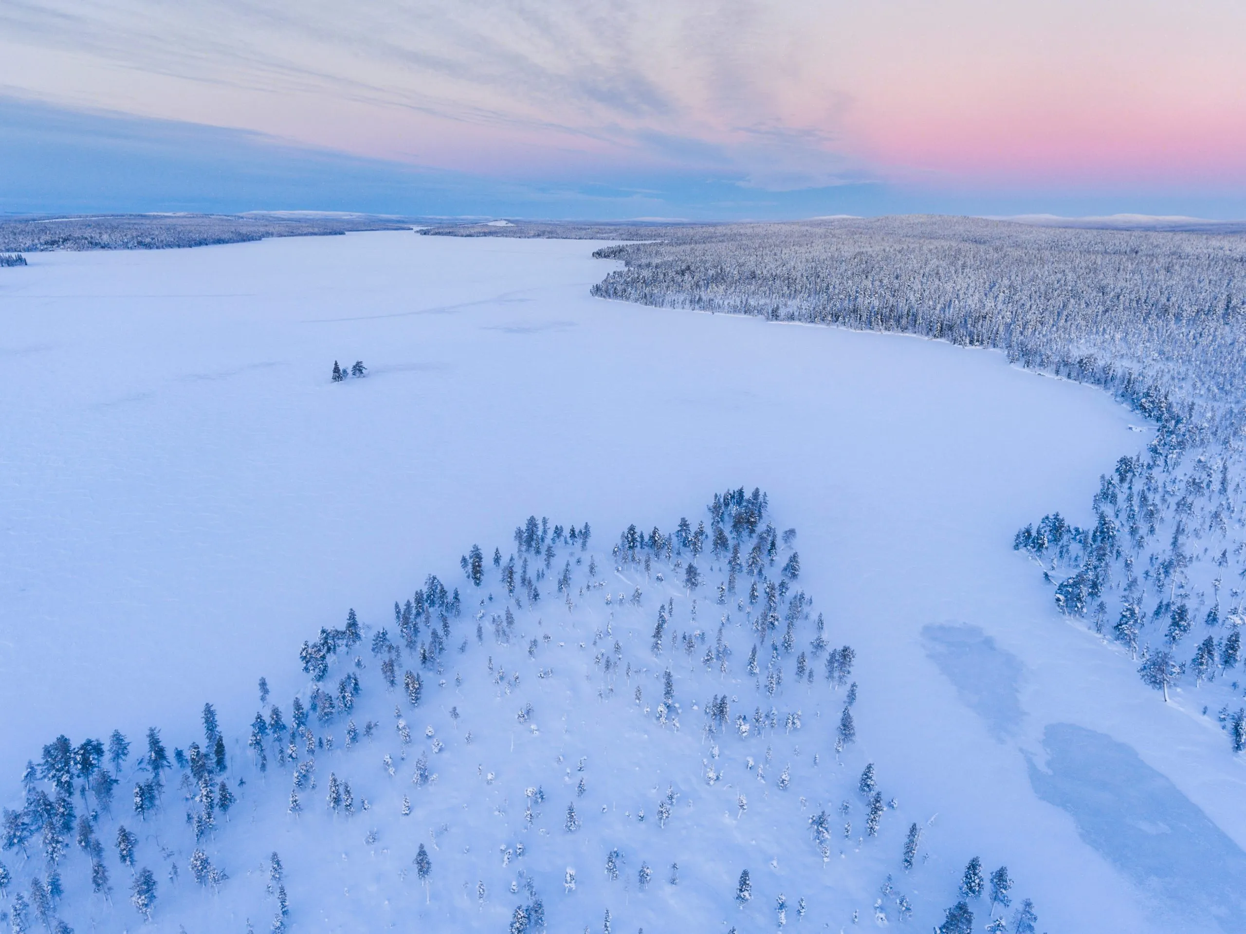 Snow covered lake and forest winter landscape showing amazing Lapland scenery in Scandinavia in Finland drone