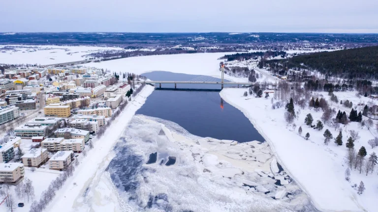 Beautiful winter landscape with buildings and a bridge over Ounasjoki River in Rovaniemi, Finland